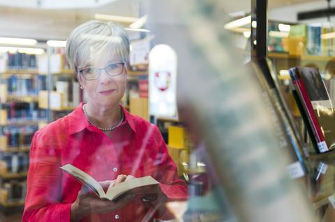 Portrait of senior woman behind glass pane in a city library stock photo