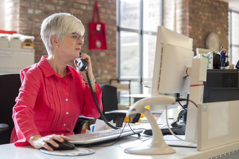 Librarian at desk on the phone in a city library stock photo