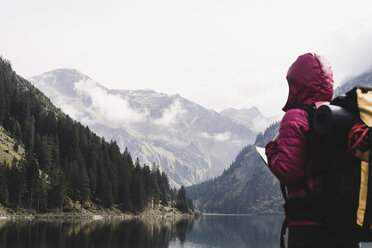 Austria, Tyrol, Alps, hiker standing at mountain lake - UUF11947