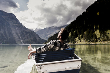 Austria, Tyrol, Alps, relaxed man in boat on mountain lake - UUF11963