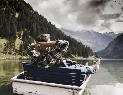 Austria, Tyrol, Alps, relaxed man in boat on mountain lake - UUF11964