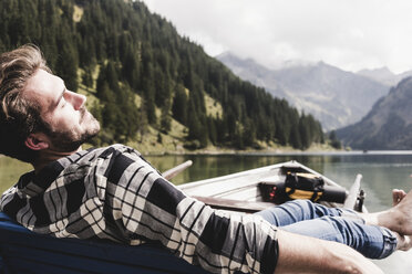 Austria, Tyrol, Alps, relaxed man in boat on mountain lake - UUF11965
