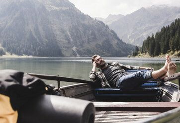 Austria, Tyrol, Alps, relaxed man in boat on mountain lake - UUF11966