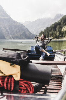 Österreich, Tirol, Alpen, entspannter Mann in Boot auf Bergsee - UUF11967