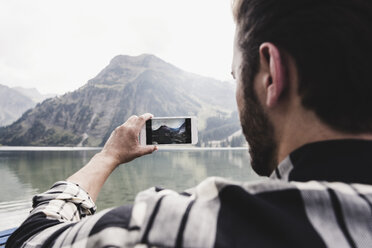 Austria, Tyrol, Alps, man taking cell phone picture of mountainscape - UUF11968