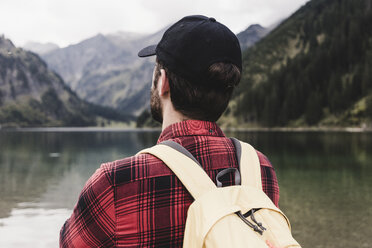 Austria, Tyrol, Alps, rear view of hiker at mountain lake - UUF11984