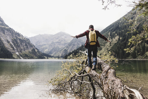 Österreich, Tirol, Alpen, Wanderer balanciert auf Baumstamm an Bergsee - UUF11989