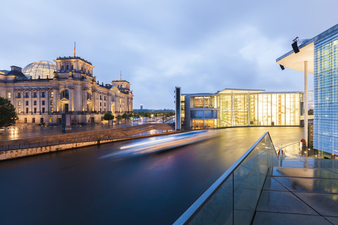 Deutschland, Berlin, Blick auf beleuchteten Reichstag und Paul-Loebe-Gebäude mit Spree im Vordergrund, lizenzfreies Stockfoto