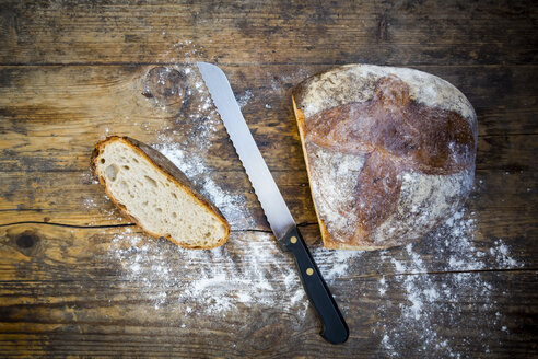 Weizenbrot mit Mehl bestäubt und Brotmesser auf dunklem Holz schneiden - LVF06353