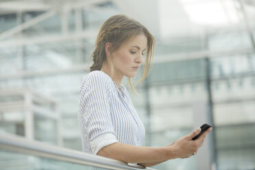 Ernste Frau, die ihr Mobiltelefon überprüft - PNEF00212