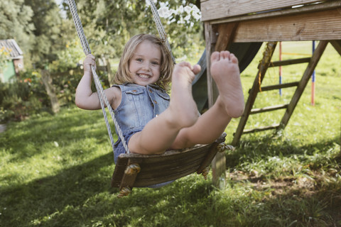 Happy little girl on swing in the garden stock photo