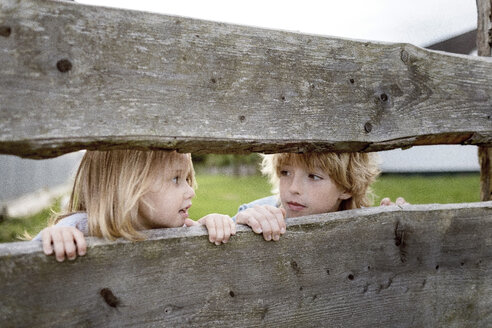 Brother and his little sister behind wooden fence - KMKF00024