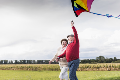 Happy senior couple with kite in rural landscape stock photo