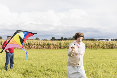 Älteres Paar lässt Drachen in ländlicher Landschaft steigen, lizenzfreies Stockfoto