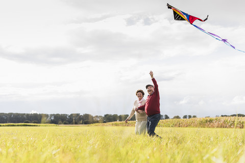 Happy senior couple flying kite in rural landscape stock photo