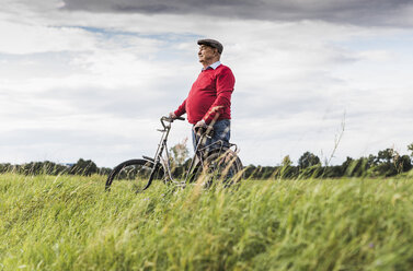 Älterer Mann mit Fahrrad in ländlicher Landschaft - UUF12015