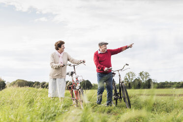 Älteres Paar mit Fahrrädern in ländlicher Landschaft - UUF12026