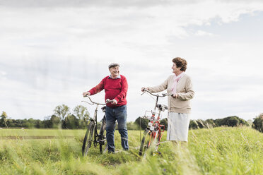 Senior couple pushing bicycles in rural landscape - UUF12027