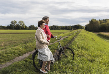 Älteres Paar mit Fahrrädern in ländlicher Landschaft - UUF12033