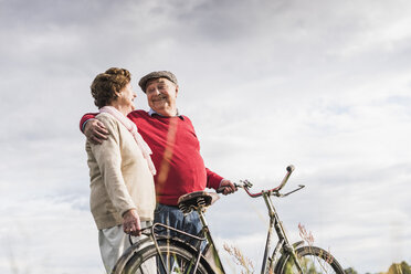 Happy senior couple with bicycles embracing - UUF12034