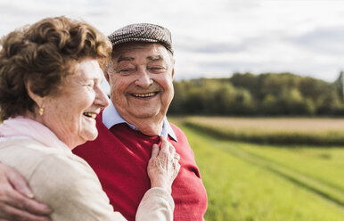 Glückliches älteres Paar, das sich in ländlicher Landschaft umarmt - UUF12036