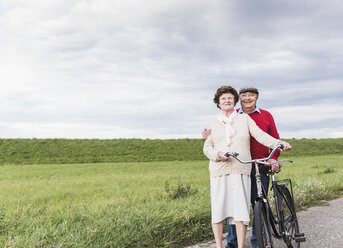 Älteres Paar mit Fahrrädern in ländlicher Landschaft - UUF12045