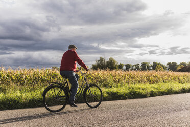 Älterer Mann fährt Fahrrad auf einem Feldweg - UUF12048