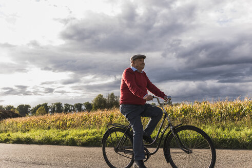 Älterer Mann fährt Fahrrad auf einem Feldweg - UUF12049