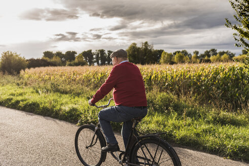 Älterer Mann fährt Fahrrad auf einem Feldweg - UUF12050