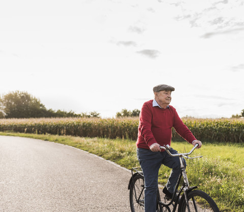 Älterer Mann fährt Fahrrad auf einem Feldweg, lizenzfreies Stockfoto