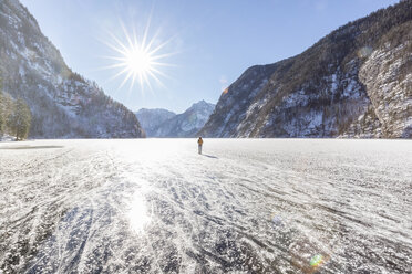 Germany, Berchtesgadener Land, back view of woman with backpack standing on frozen Lake Koenigssee - MMAF00155