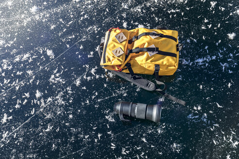 Deutschland, gelber Rucksack und Objektiv auf dem zugefrorenen Königssee liegend - MMAF00157