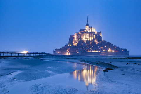 Frankreich, Blick auf den beleuchteten Mont Saint-Michel bei Ebbe und blauer Stunde, lizenzfreies Stockfoto