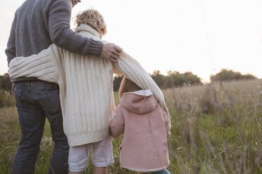 Father with two children standing at a field at sunrise - KMKF00034