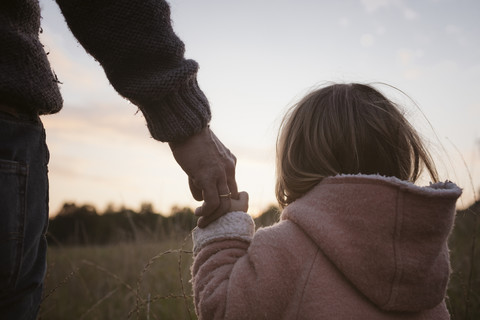 Father with daughter standing at a field at sunrise stock photo