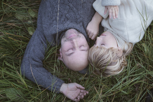 Father with son lying in meadow - KMKF00039