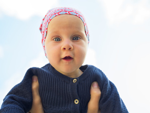 Porträt von erstaunt Baby Mädchen gegen Himmel, lizenzfreies Stockfoto