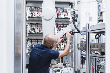 Mann arbeitet an einem Industrieroboter in einer modernen Fabrik - DIGF02929