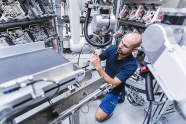 Mann arbeitet an einem Industrieroboter in einer modernen Fabrik - DIGF02933