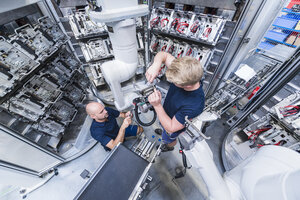 Two colleagues working at industrial robot in modern factory - DIGF02938