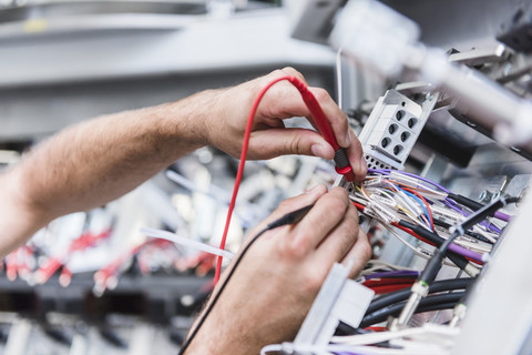 Nahaufnahme eines Mannes, der ein Voltmeter in einer Fabrik benutzt, lizenzfreies Stockfoto