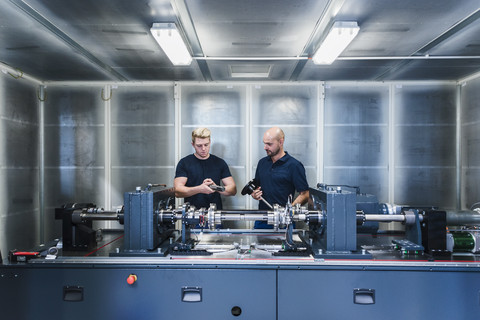 Zwei Kollegen arbeiten in einer modernen Fabrik, lizenzfreies Stockfoto