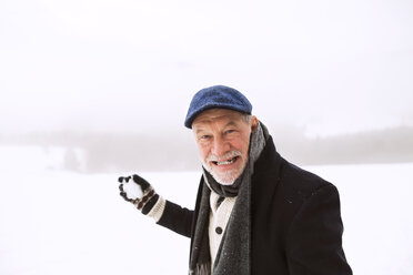 Portrait of senior man holding snowball - HAPF02227