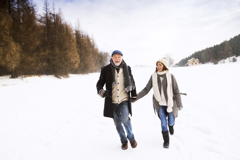 Glückliches älteres Paar beim Spaziergang in verschneiter Landschaft, lizenzfreies Stockfoto