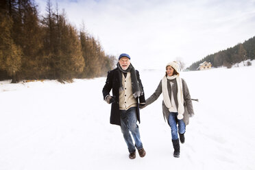 Glückliches älteres Paar beim Spaziergang in verschneiter Landschaft - HAPF02234