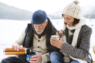 Älteres Ehepaar bei einer Pause mit heißen Getränken in verschneiter Winterlandschaft - HAPF02262