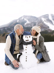 Älteres Paar mit Schneemann in Winterlandschaft - HAPF02271