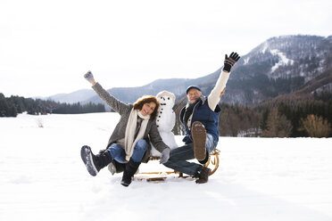 Älteres Paar posiert mit Schneemann auf Schlitten in Winterlandschaft - HAPF02274