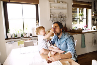 Father having fun with little boy sitting on kitchen table - HAPF02282