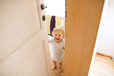 Porträt eines glücklichen kleinen Jungen, der die Tür öffnet - HAPF02288